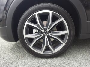 Nahaufnahme eines VW-Autoreifens mit grauen Felgen auf Kieselsteinen.