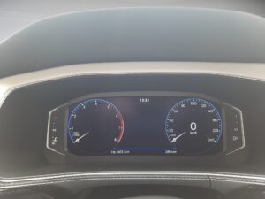 Digitales Armaturenbrett eines Autos, zeigt Geschwindigkeit 0 km/h und Drehzahlmesser.