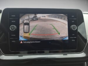 Rückfahrkamera-Ansicht eines Autos, zeigt Parkplatz mit grünen und roten Linien.