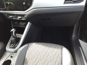 Innenraum eines Autos mit schwarzem Armaturenbrett, grauem Sitz und modernem Schalthebel.