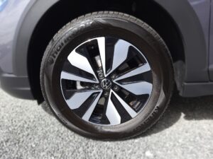 Nahaufnahme eines schwarzen Autoreifens mit glänzender Felge und silbernen Details.