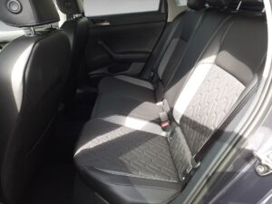 Rücksitze eines Autos mit schwarzen Polstern und abgestepptem Muster, in einem sonnigen Innenraum.