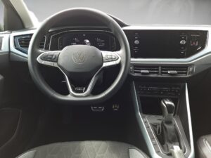 Lenkrad und Armaturenbrett eines modernen Autos in Schwarz und Silber mit Volkswagen-Logo.