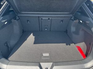 Offener Kofferraum eines Autos mit grauem Teppichboden und einer roten Notfallausrüstung.