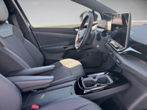 Innenraum eines Autos mit schwarzem und grauem Interieur, großem Display und roten Nähten.