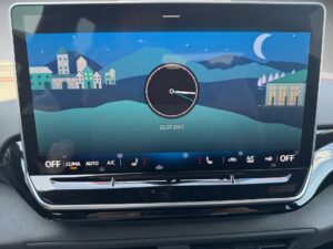 Ein Auto-Display zeigt eine nächtliche Stadtlandschaft mit Uhr- und Datumanzeige.