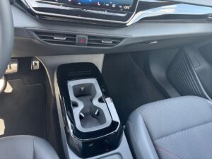 Autoinnenraum mit glänzendem schwarzen Becherhalter, grauem Sitz und Pedalen am Fußraum.