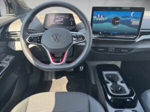 Innenraum eines Autos mit grauen Sitzen, schwarzem Lenkrad und digitalem Display.