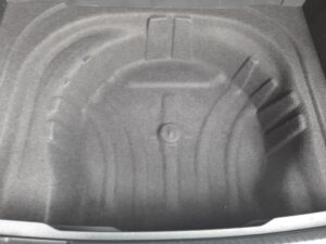 Kofferraum eines Autos mit geformter Vertiefung für ein Reserverad, schwarzer Stoffbezug.