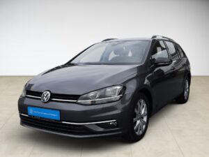 Dunkelgrauer VW Golf Kombi, glänzend lackiert, steht in einem minimalistischen Raum auf hellen Fliesen.