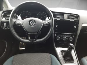 Lenkrad und Mittelkonsole eines Volkswagen, schwarz, klar angeordnete Bedienelemente.