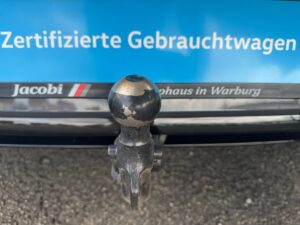 Anhängerkupplung an Fahrzeug mit blauem Schild: Zertifizierte Gebrauchtwagen. Robust, metallisch.