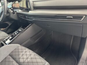 Innenraum eines Autos, graue Sitze mit Muster, moderner Armaturenbrett, Lenkrad links.