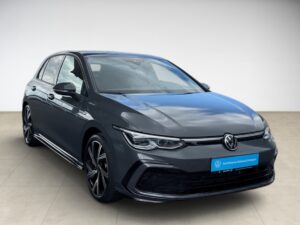 Graues Volkswagen-Auto, Seitenansicht, moderne Scheinwerfer, blaues Schild vorne.