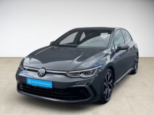 Grauer Volkswagen Golf mit modernen Scheinwerfern, auf beigem Boden in hellem Raum fotografiert.