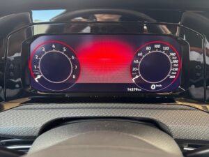 Nahaufnahme eines Auto-Armaturenbretts mit digitalem Tacho, rotem Hintergrund, spiegelnde Anzeige.
