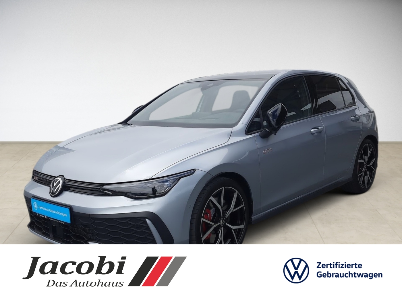 Grauer Volkswagen Golf von vorn, schwarze Felgen, Display zeigt Jacobi Autohaus und VW-Logo.