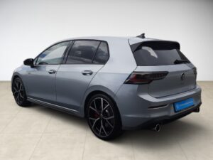 Ein grauer VW Golf GTI in Seitenansicht, sportliches Design und schwarz-rote Felgen.