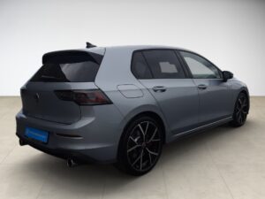 Ein graues Auto steht seitlich, hervorstehende Rücklichter und schwarze Felgen.