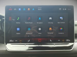 Nahaufnahme eines Auto-Infotainment-Bildschirms mit verschiedenen App-Symbolen und Klimasteuerung.