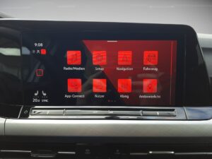 Bildschirm in einem Auto mit rotem Interface und Symbolen für Medien, Setup, Navigation und Fahrzeug.