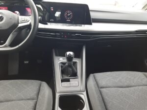 Ein moderner Auto-Innenraum mit Schalthebel und digitalem Display, zeigt Uhrzeit.