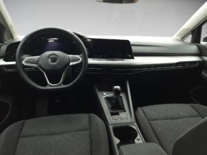 Innenraum eines Autos mit schwarzem Lenkrad, grauem Armaturenbrett und einem Schalthebel.