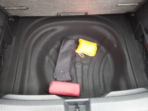 Kofferraum mit leeren Fächern, schwarzer Tasche, gelbem und rotem Beutel auf dem Boden.
