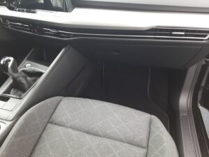 Innenraum eines Autos, grauer Sitzstoff, schwarzes Armaturenbrett, Schalthebel sichtbar, modern.