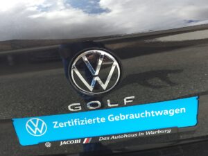Ein Volkswagen-Emblem auf glänzendem schwarzen Auto mit blauem Aufkleber.