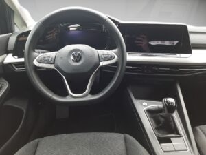 Lenkrad und Schalthebel eines modernen Autos, schwarz, Volkswagen-Logo sichtbar.