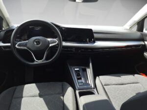 Innenraum eines modernen Autos mit grauen Sitzen und einem schwarzen Lenkrad mit VW-Logo.