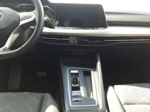 Innenraum eines Autos mit modernem Armaturenbrett und zentralem Bildschirm, Schwarz-Grau-Töne.