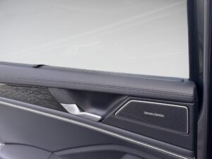Autotür-Innenverkleidung mit grauem Leder, silbernem Griff und Lautsprecher, modernes Design.