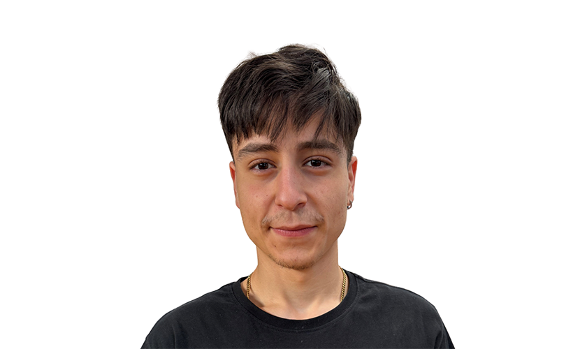 Eine lächelnde Person mit dunklem Haar und schwarzem Hemd vor weißem Hintergrund