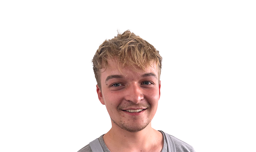 Eine lächelnde Person mit blondem Haar in einem grauen T-Shirt vor weißem Hintergrund