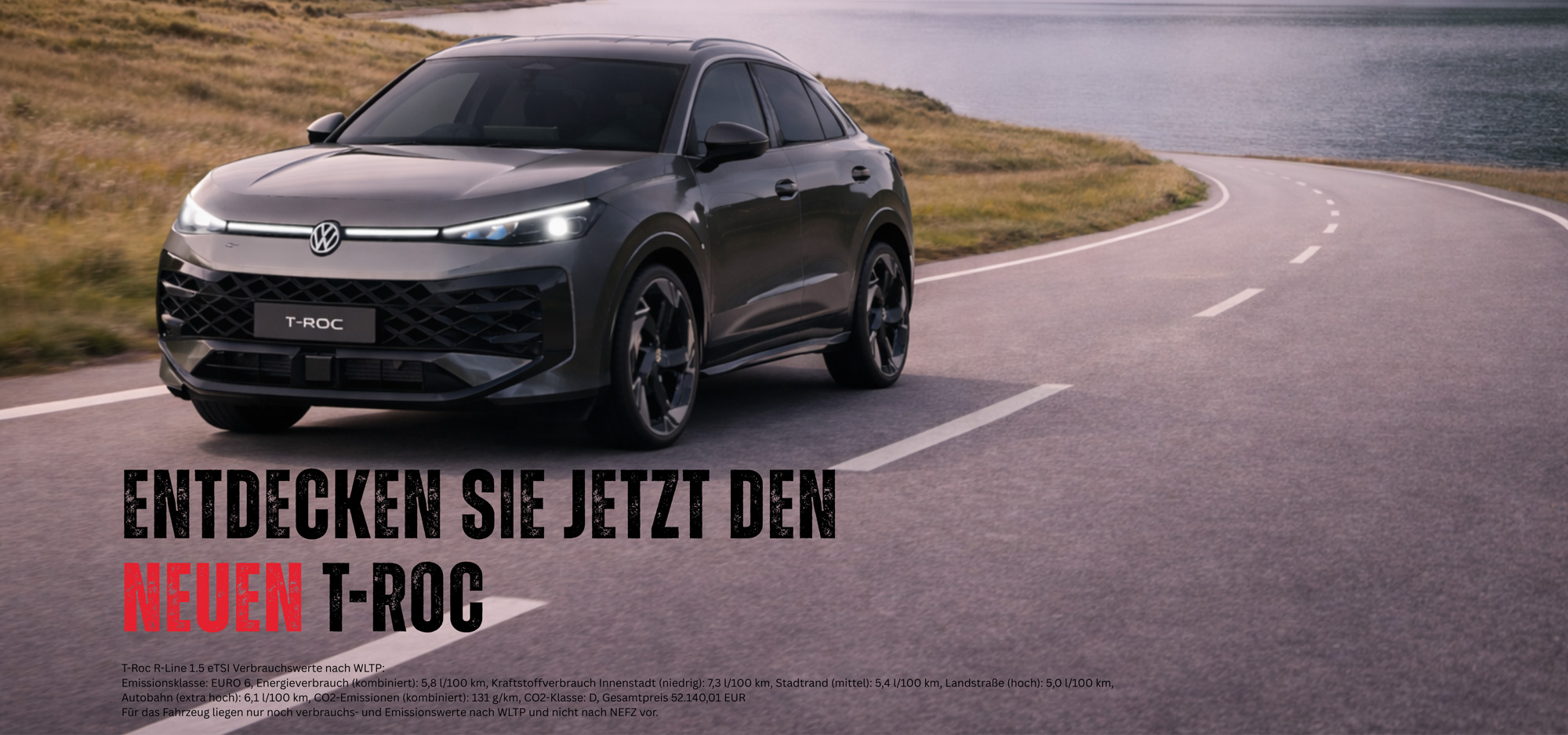 Ein silbergrauer Volkswagen T-Roc fährt auf einer kurvigen Straße am Wasser entlang