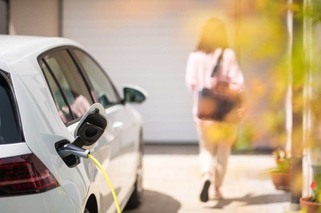 Nahaufnahme eines Ladegeräts für Elektroautos mit der Silhouette einer Frau im